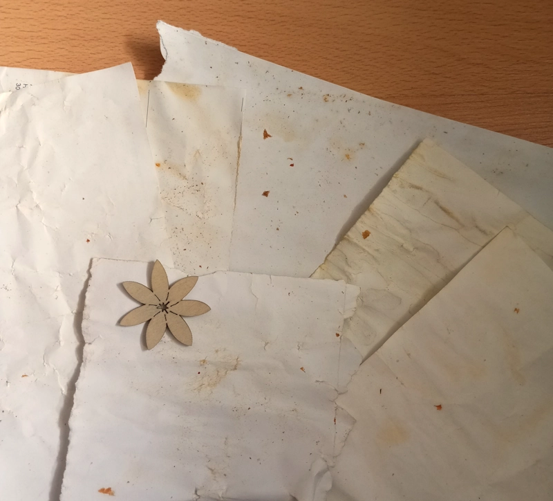 Papier färben mit Naturmaterialien: Papier, das mit Karottenschalen gefärbt wurde und einen schönen Vintage-Look erhalten hat. Zur Dekoration ist eine kleine Holzblume mit auf dem Bild.