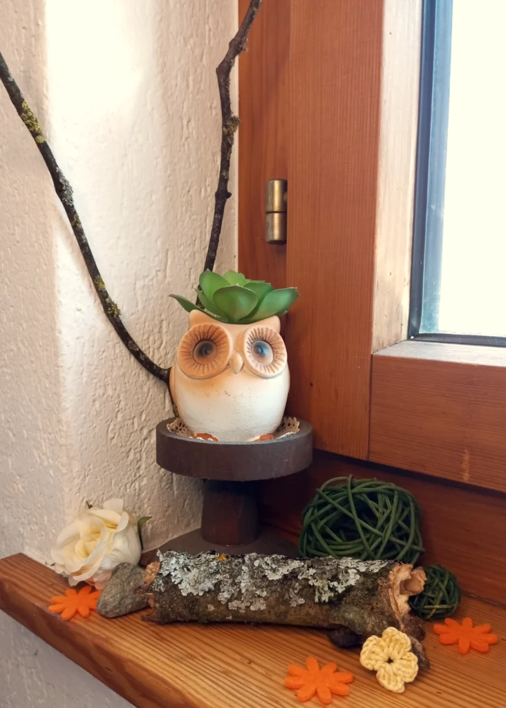Dekorieren mit Naturmaterialien: Eulenfigur mit Sukkulente, Ästen und Filzblumen auf Fensterbrett