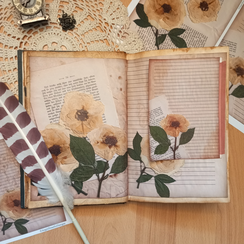 Aufgeschlagesnes Journal, das mit selbstgemachten, linnierten Papieren dekoriert ist. Darauf sind gepresste, weiße Rosen.