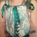 Nahaufnahme eines getragenen, weißen Korsets. Grüne Aufdrucke von Trauben - 3 Tattoos auf den Armen