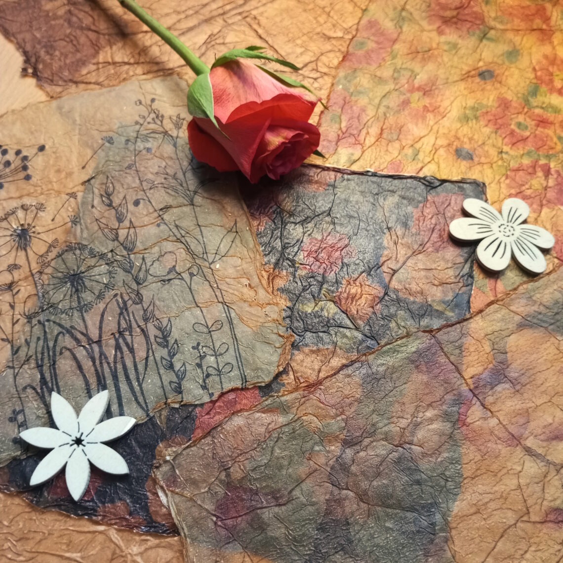 Selbstgemachte Bastelpapiere aus Servietten im Vintage-Stil, dekoriert mit einer Rose und Blumen aus Holz