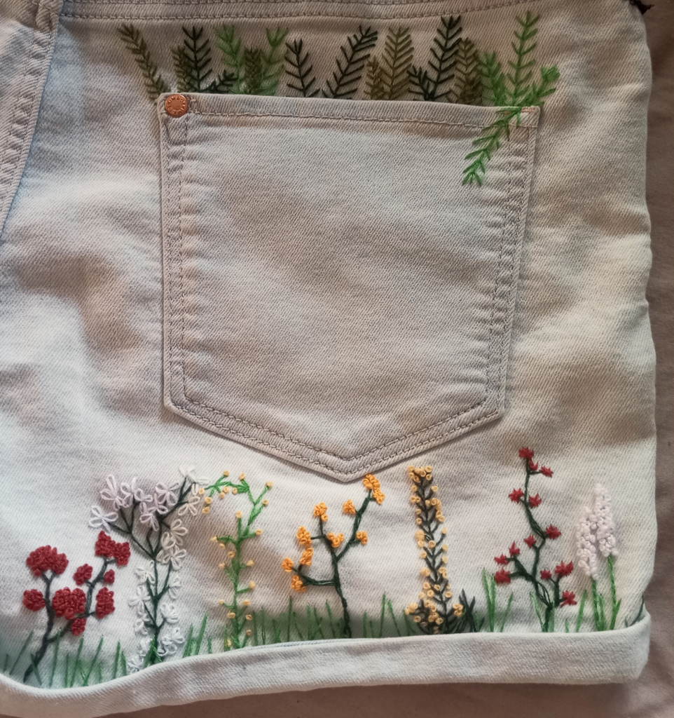 Stickarbeit einer Blumenwiese und von gesticktem Farn auf der Hinterseite eines Overalls
