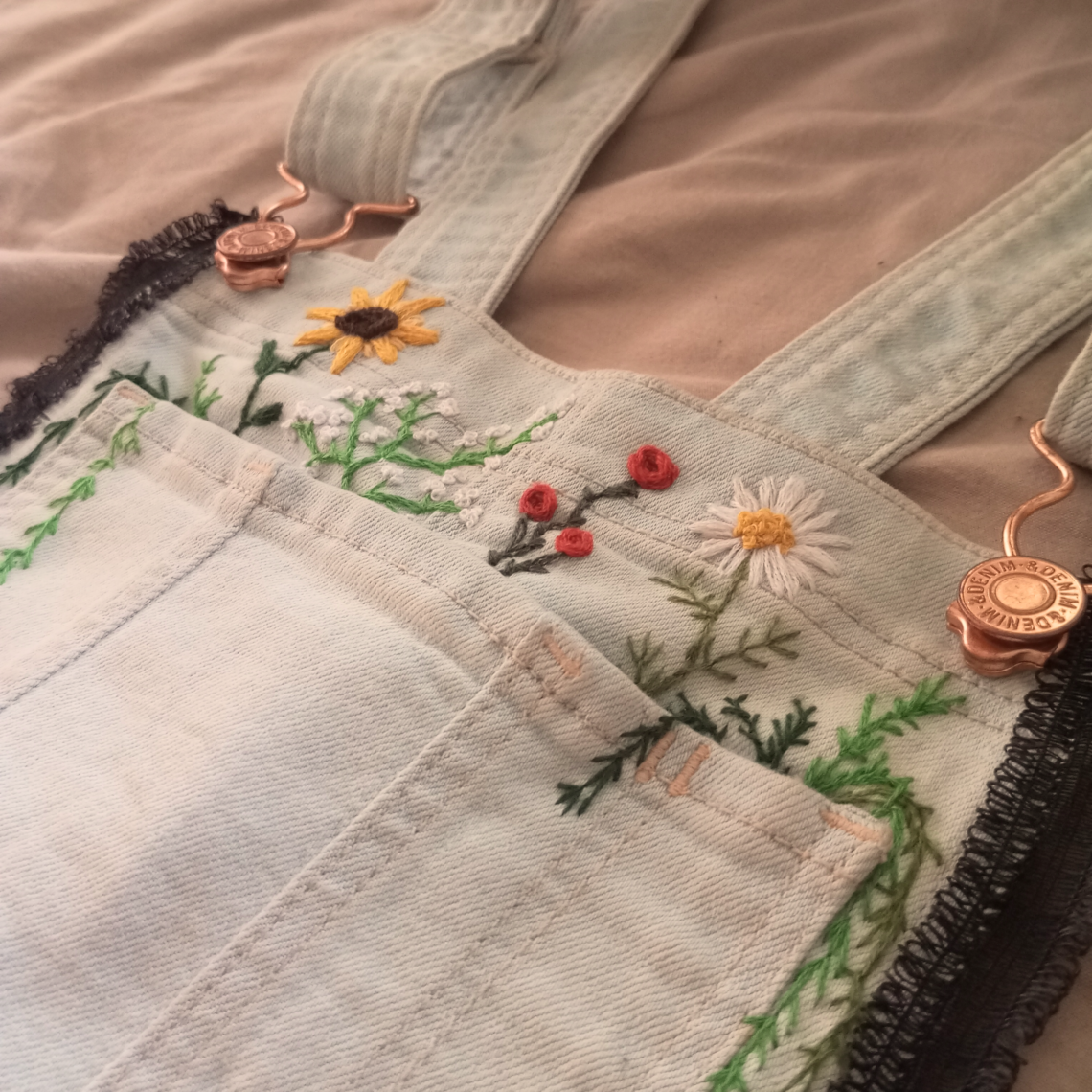 Nahaufnahme non gestickten Blumen über der Brusttasche einer Latzhose