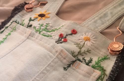 Nahaufnahme non gestickten Blumen über der Brusttasche einer Latzhose