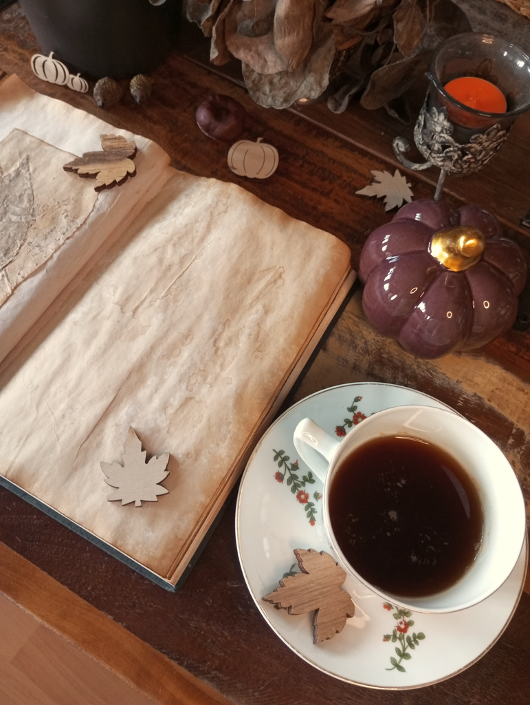 ein aufgeschlagenes, altes Journal, eine Tasse Kaffee und herbstliche Dekorationen