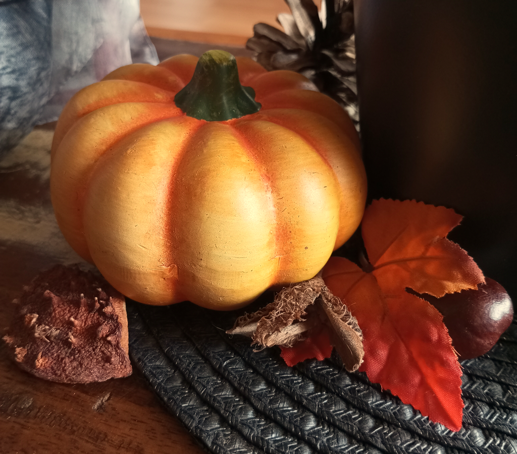 Herbstdekoration mit einem Kürbis, einem roten Blatt und Kastanienschalen